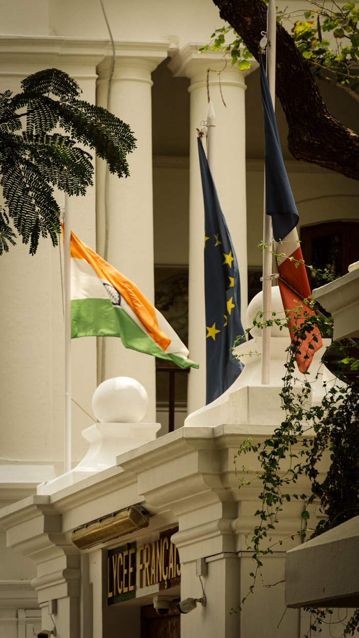 Vertical shot of flags at Lycée Français in Puducherry, India, showcasing colonial architecture.